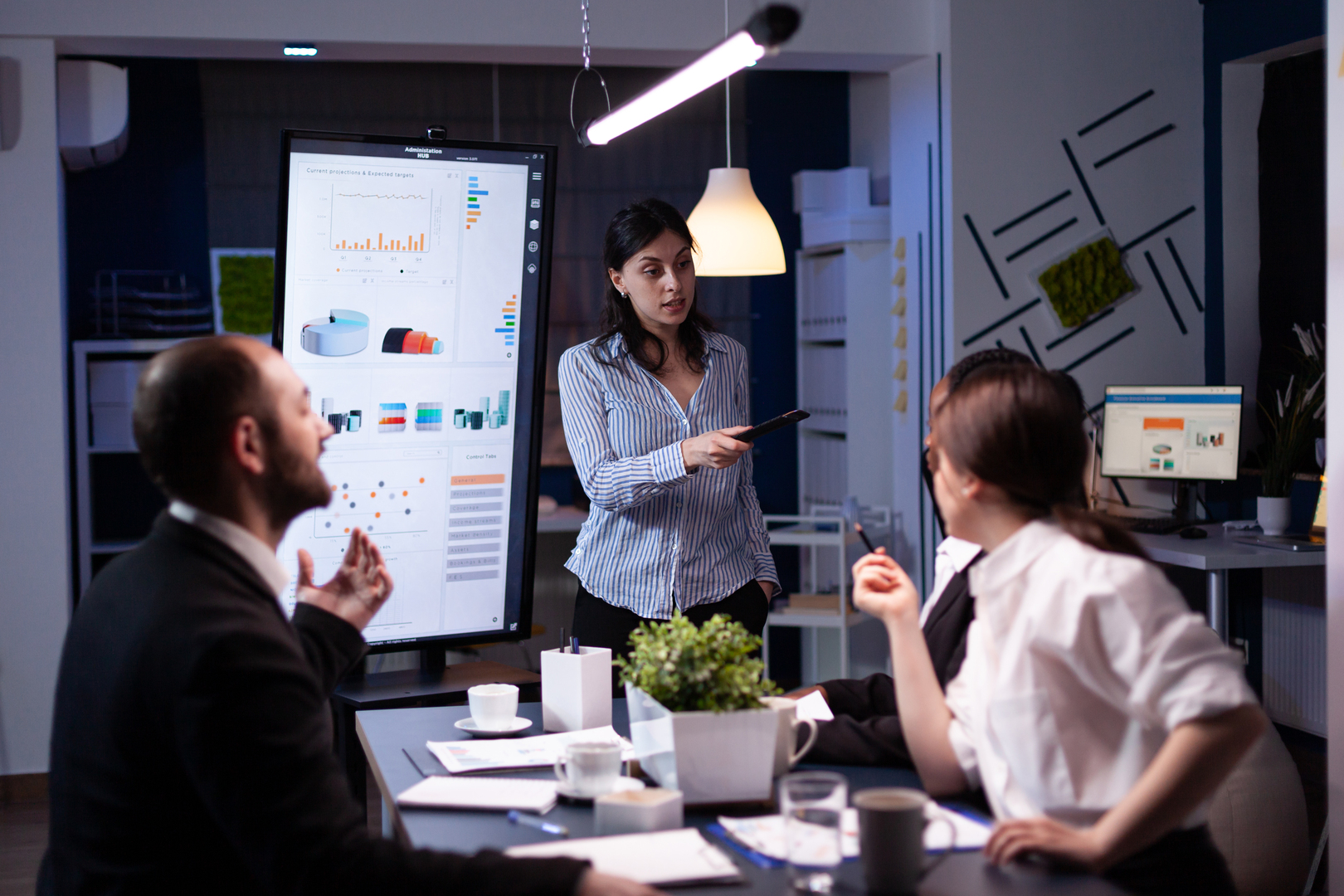 Workaholic businesswoman pointing financial strategy using monitor working overtime